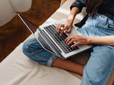 Schülerin auf dem Sofa mit Laptop auf dem Schoß