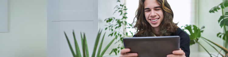 Abiturient lernt fröhlich mit Tablet in der Hand